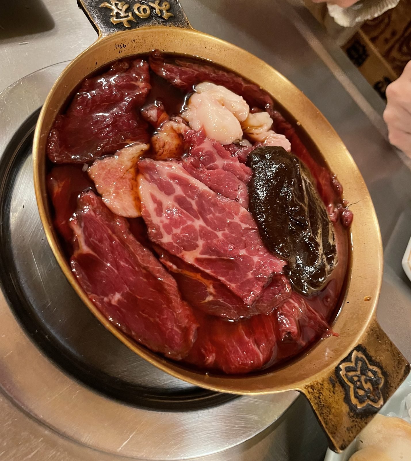 Olla de latón con sukiyaki de carne de caballo (sakura nabe) sobre un hornillo