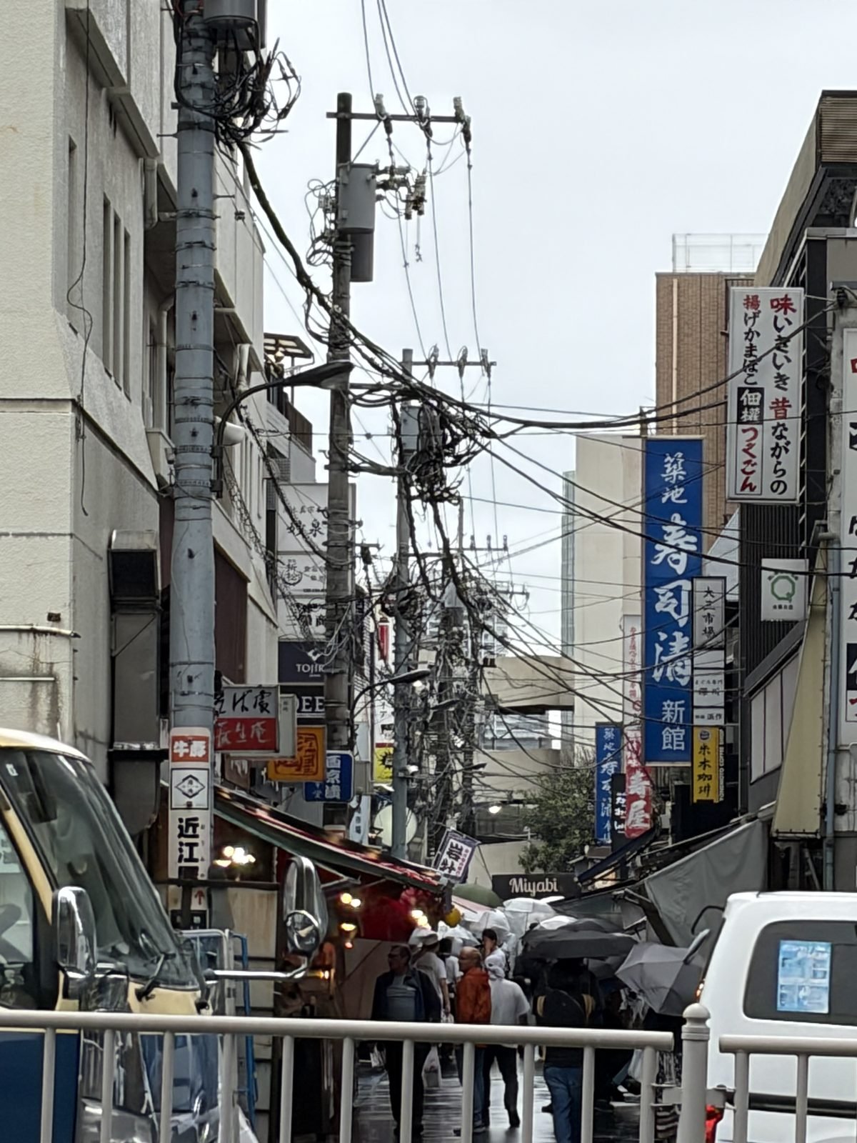 Callejuela del mercado exterior de Tsukiji con paraguas transparentes y cables eléctricos